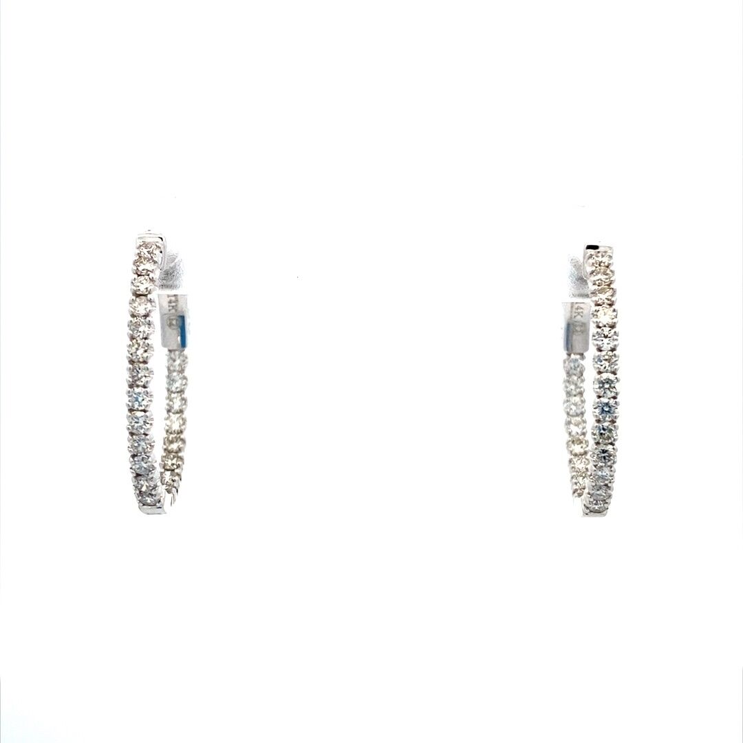 A pair of 14 karat white gold oval hoops set with diamonds