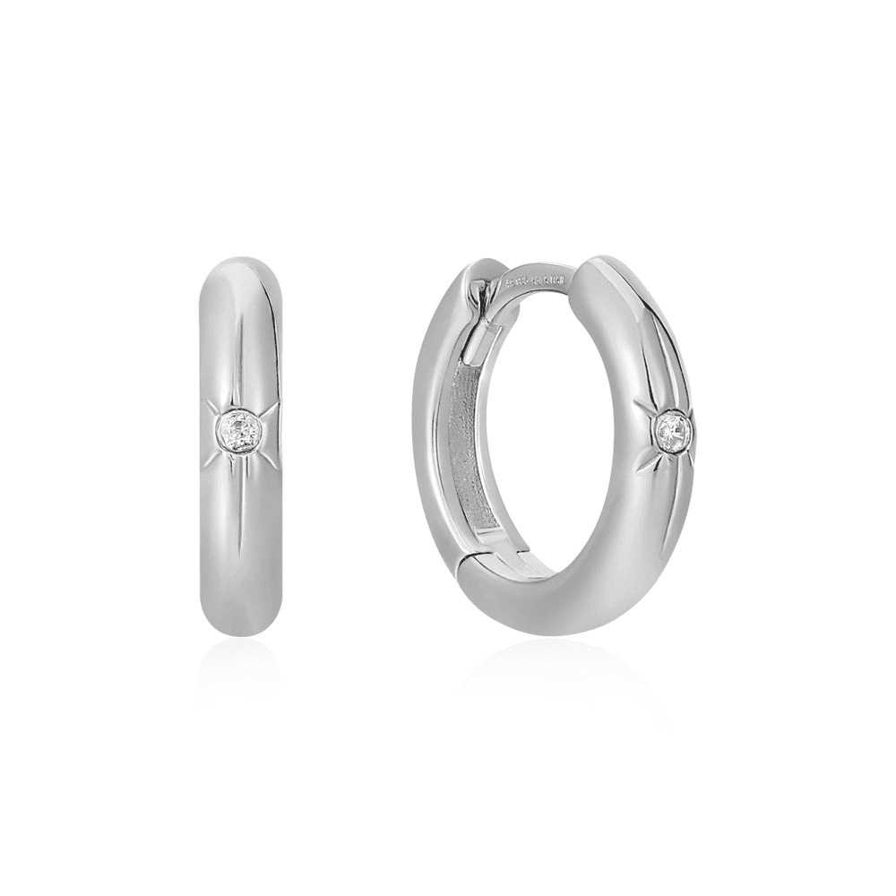 A pair of sterling silver huggie hoop earrings with a single cubic zirconia set in the front of each inside of a star accent