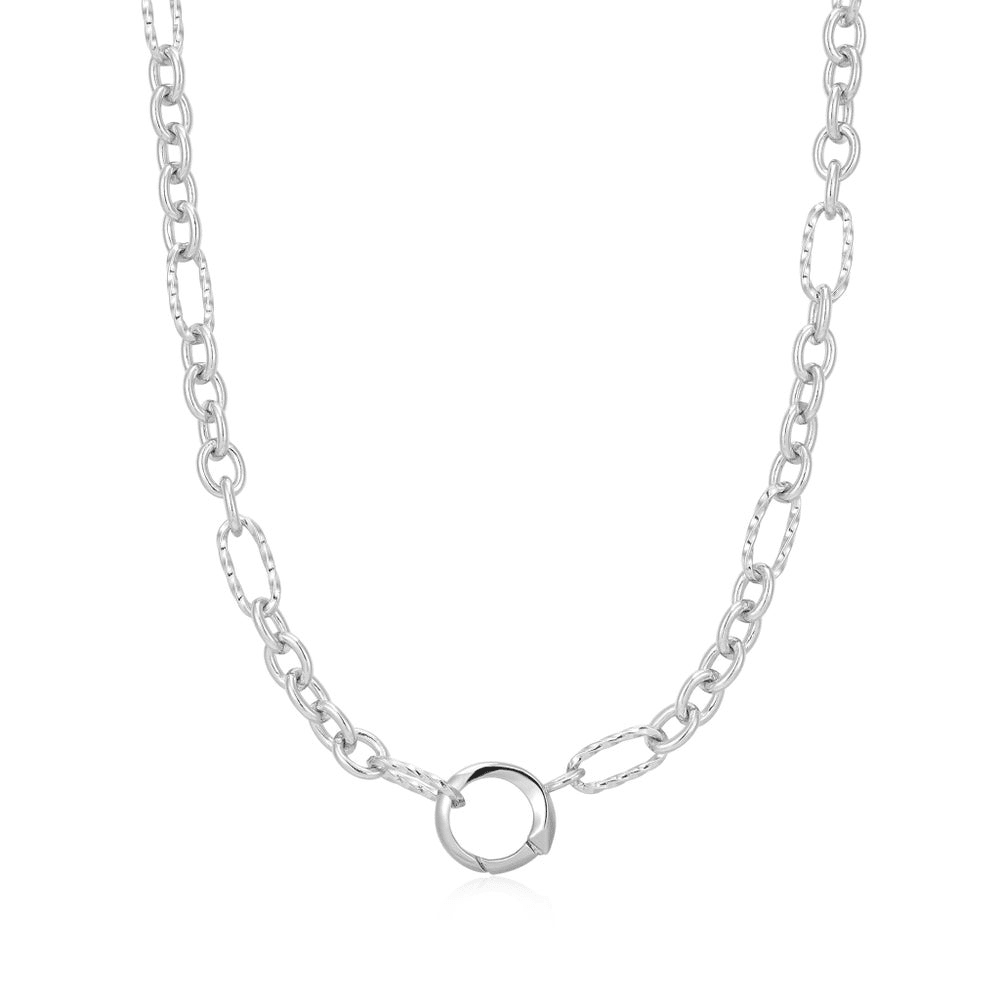 A sterling silver chain necklace with mixed shapes of links and with a ring in the center for holding charms set against a white background. From the Pop Charms Collection by Ania Haie
