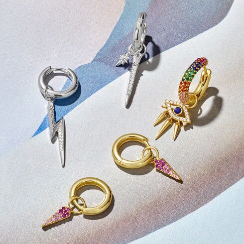 An assortment of earrings including the silver star huggie hoop earrings with charms attached