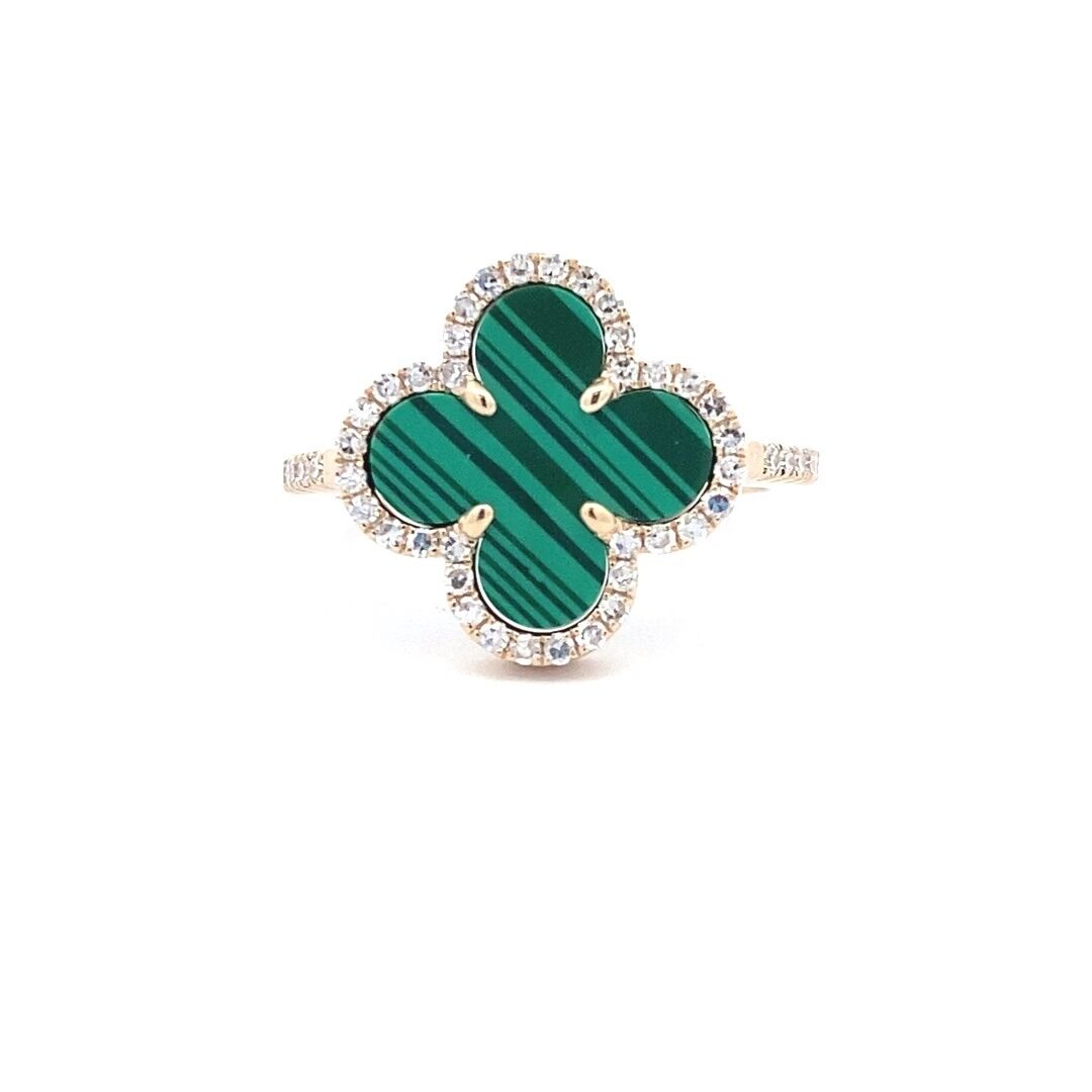 A yellow gold clover ring set with a flat piece of malachite and diamond halo