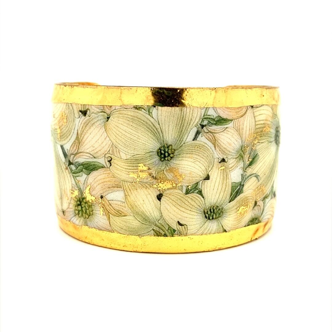 A cuff bracelet by Evocateur feature enamel images of dogwood flowers